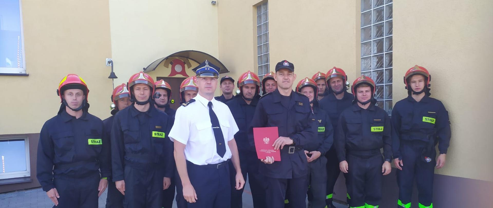 dwie zmiany służbowe, komendant powiatowy oraz awansowany mł. asp. Łukasz Roman pozują do zdjęcia.
