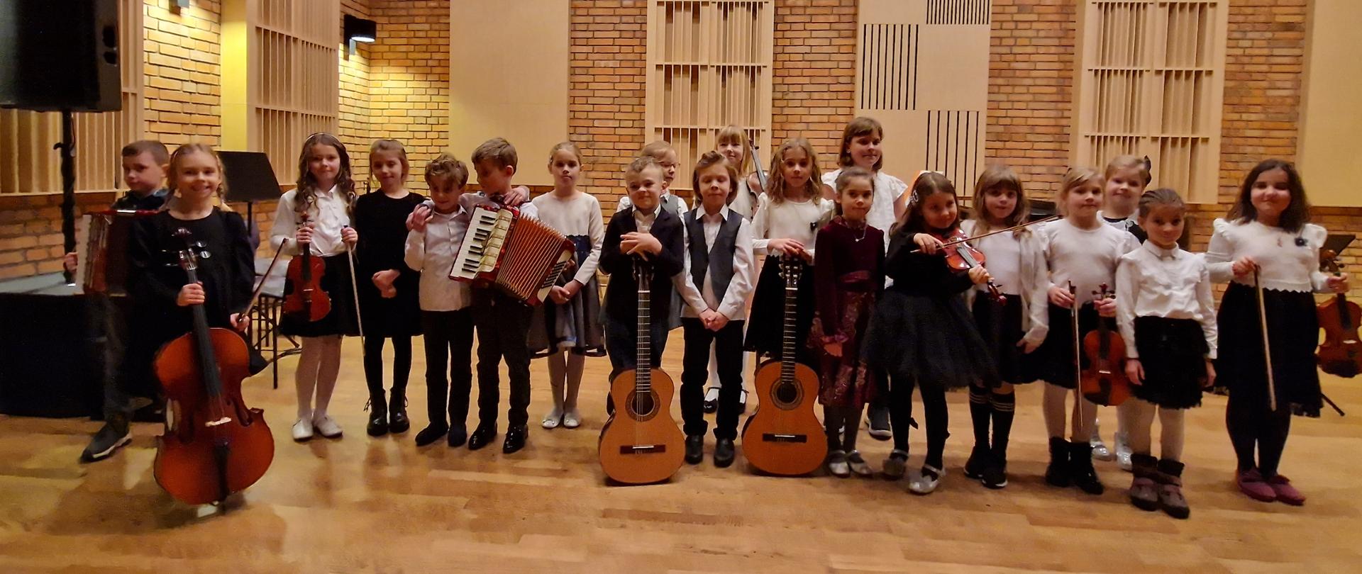 Zdjęcie zbiorowe - stojąca grupa dzieci w galowych strojach z instrumentami