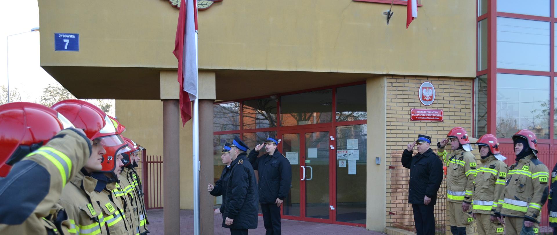 Poczet flagowy wciąga flagę na maszt, kadra dowódcza, zmiana zdająca i zmiana przyjmująca oddają honory. 