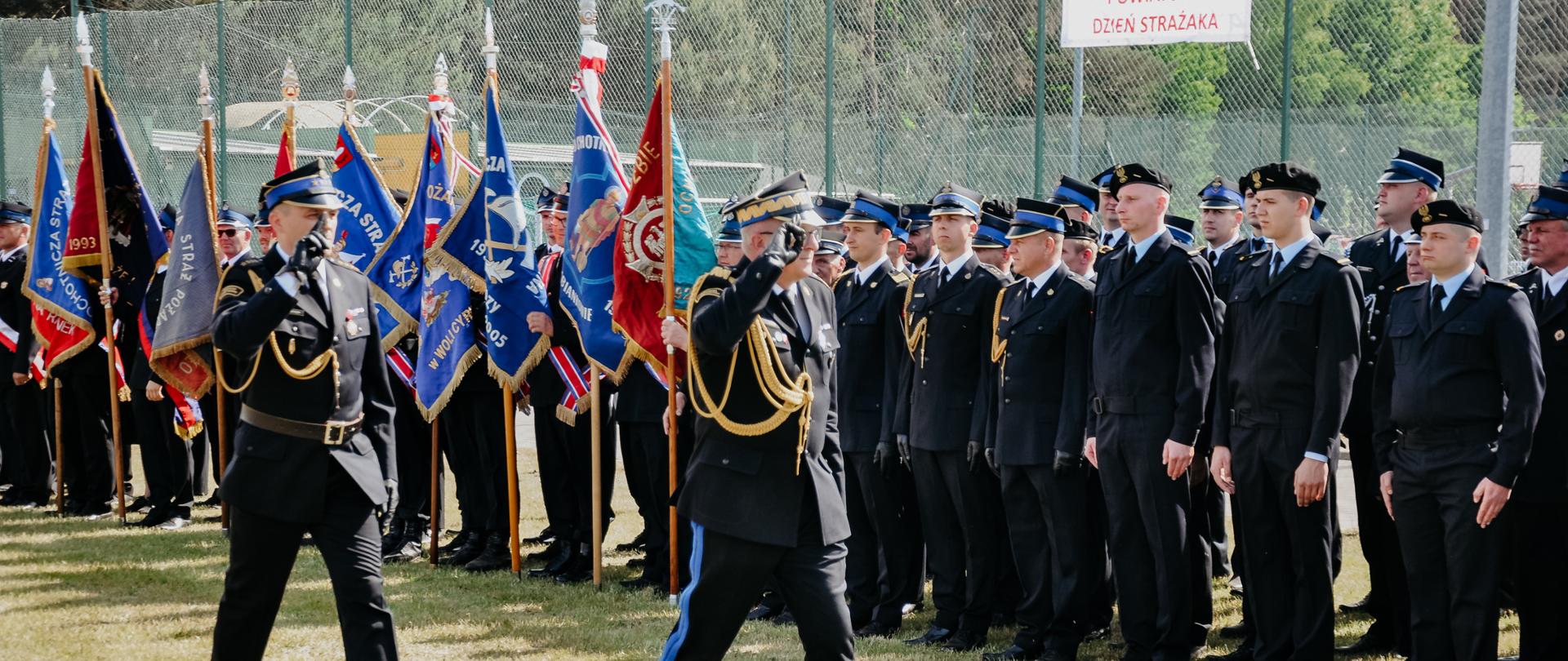 nadbryg. Krzysztof Hejduk - zastępca komendanta głównego PSP dokonuje przeglądu pododdziałów PSP OSP oraz pocztów flagowych strażacy stoją w szeregu zaś nadbrygadier idzie wzdłuż salutując