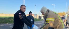 Strażacy ćwiczą zdejmowanie skażonego kombinezonu. 