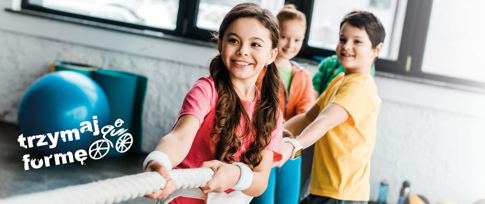 Dzieci przeciągające linę i napis :trzymaj formę"