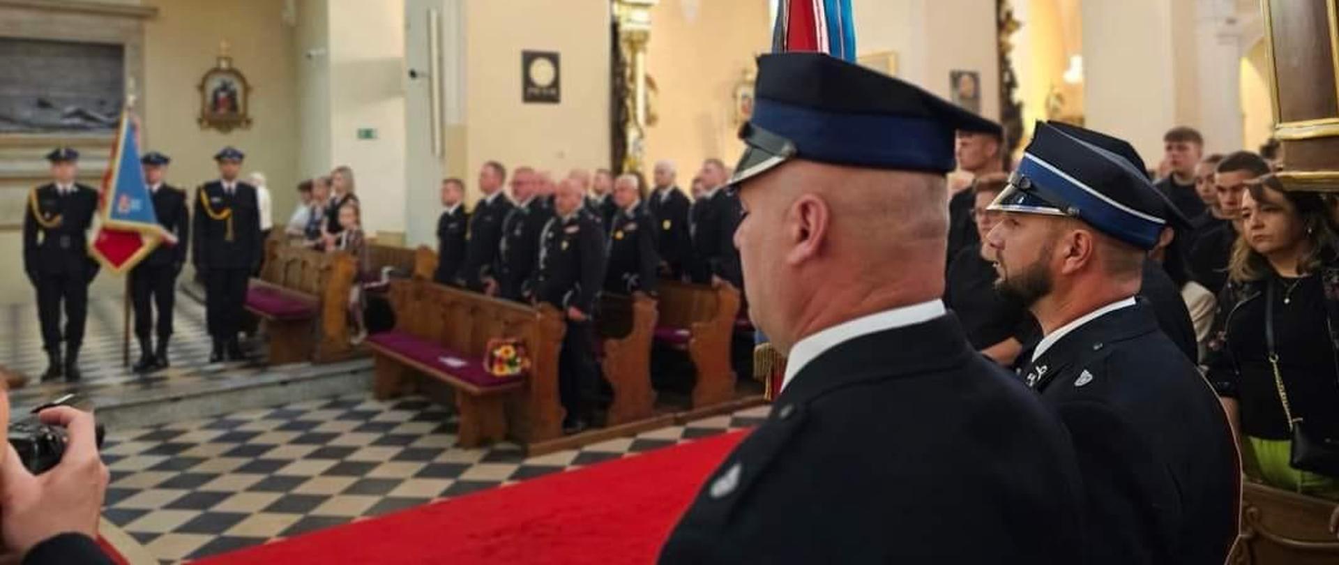 Zdjęcie przedstawia krotoszyńską bazylikę. W ławkach kościoła zasiadają strażacy uczestniczący we mszy świętej w intencji strażaków i ich rodzin. W uroczystości uczestniczy Wielkopolski Komendant Wojewódzki