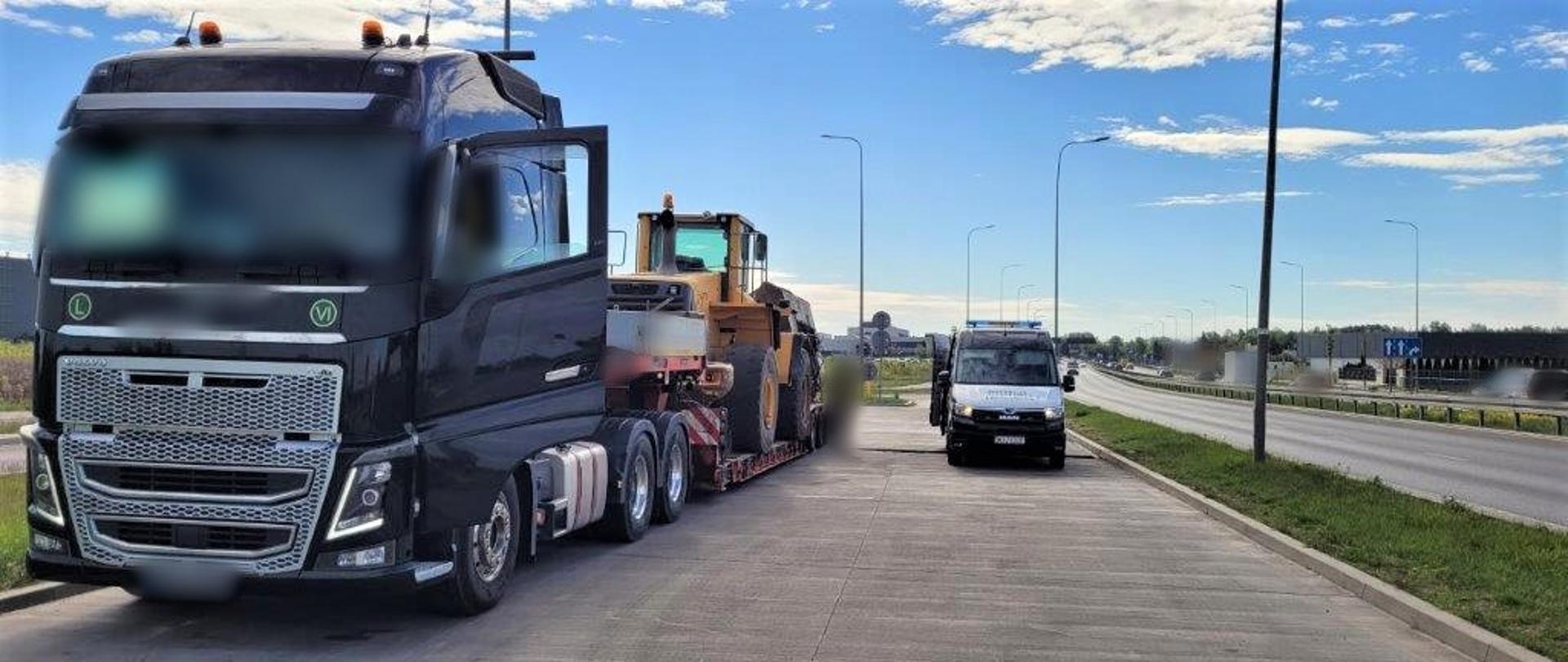 Na pierwszym planie (od lewej): kontrolowany ciągnik siodłowy z podpiętą naczepą niskopodwoziową. Na naczepie jest przewożona ładowarka z odczepioną łyżką. W tle: obok kontrolowanego zestawu ciężarowego stoi oznakowany furgon mazowieckiej Inspekcji Transportu Drogowego.
