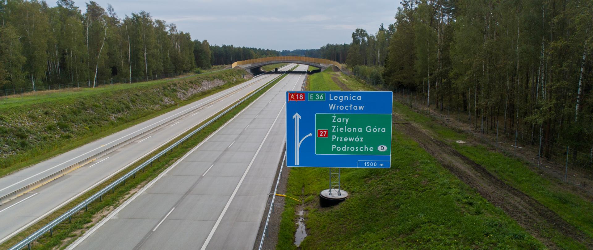 Autostrada A18 z widoczną na pierwszym planie tablicą kierunkową (Legnica, Wrocław), na dalszym planie widoczne duże przejście dla zwierząt.