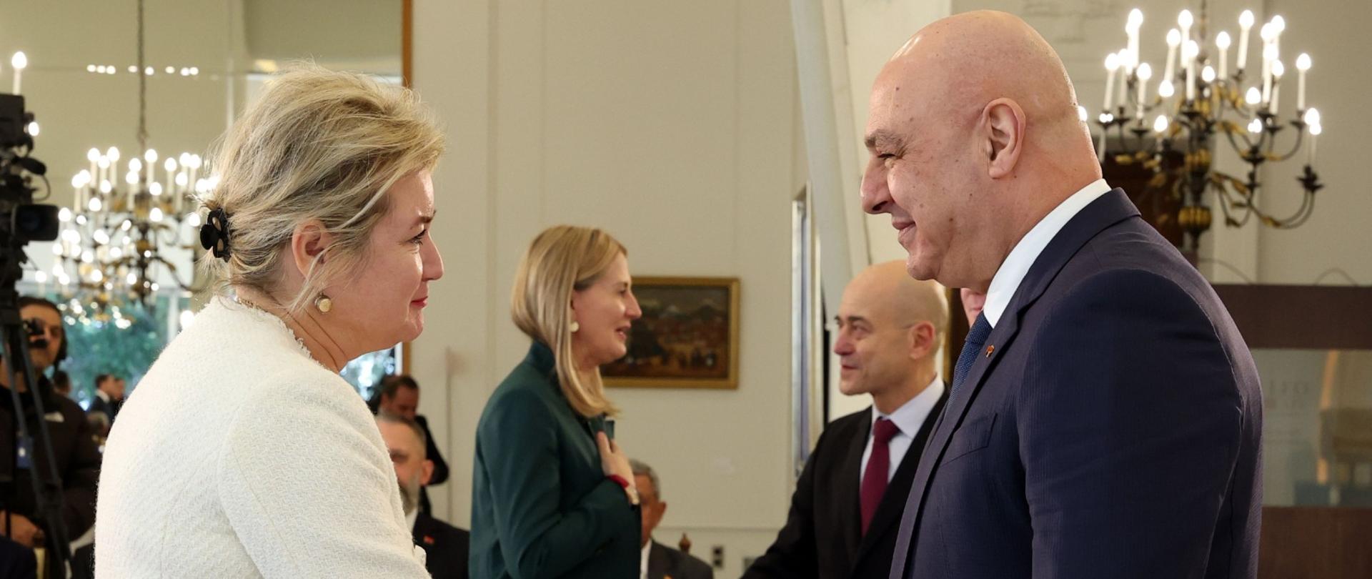 Kobieta i mężczyzna ściskają dłonie na przywitanie. Uśmiechają się do siebie. 