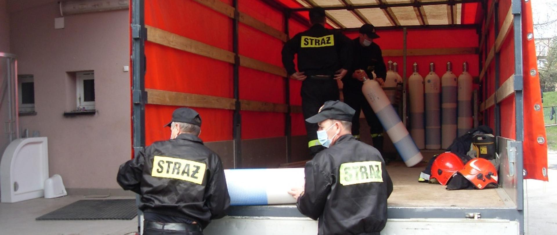 Na zdjęciu strażacy rozładowujący butle z tlenem z samochodu kwatermistrzowskiego