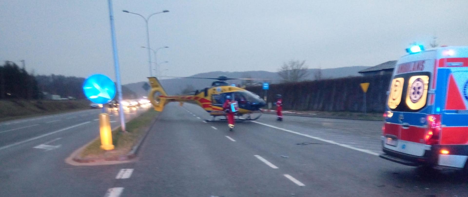 Zdjęcie przedstawia miejsce wypadku: w głębi wylądował śmigłowiec Lotniczego Pogotowia Ratunkowego. A z lewej strony stoi ambulans