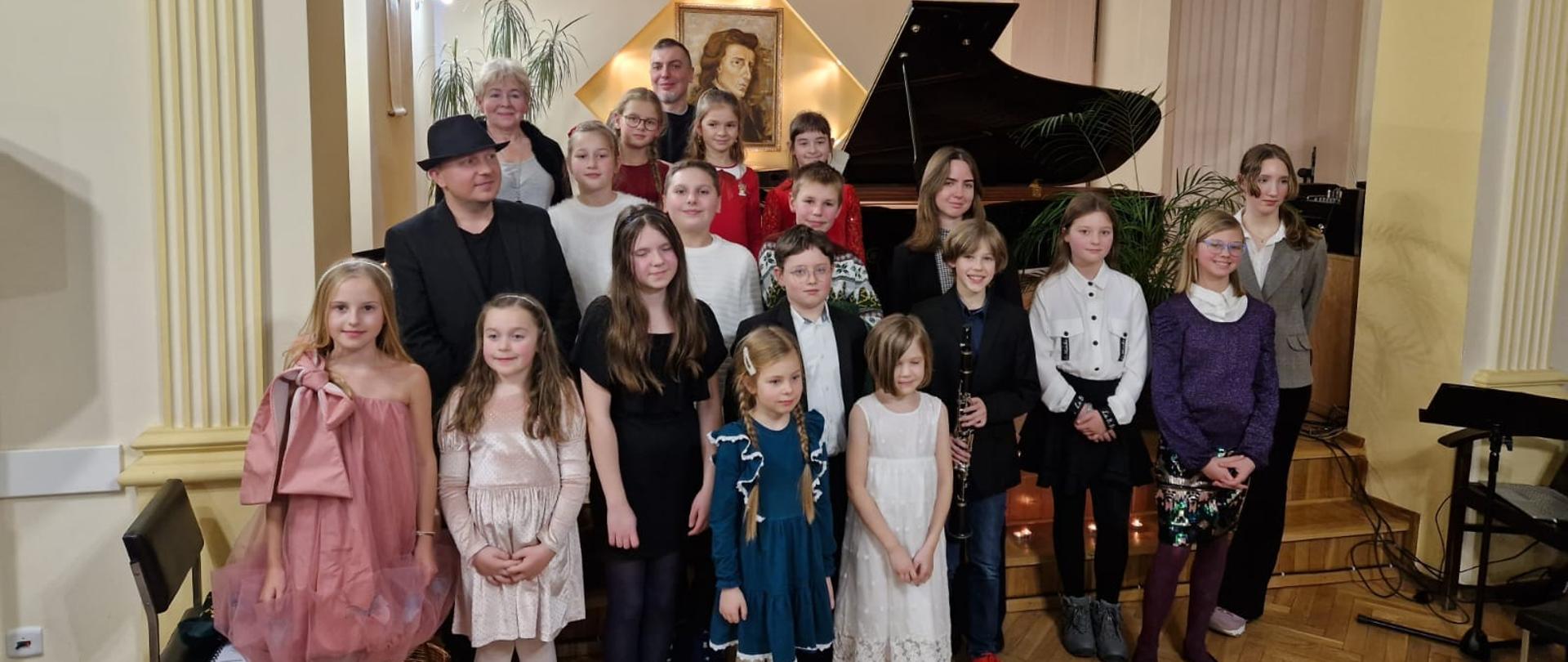 Galeria 16 zdjęć z koncertu kolęd w wykonaniu uczniów klasy P. Anny Bartkiewicz-Brzozowskiej i K. Mąki-Żelazko. Uczniowie grają na instrumentach w auli PSM w Kłodzku.