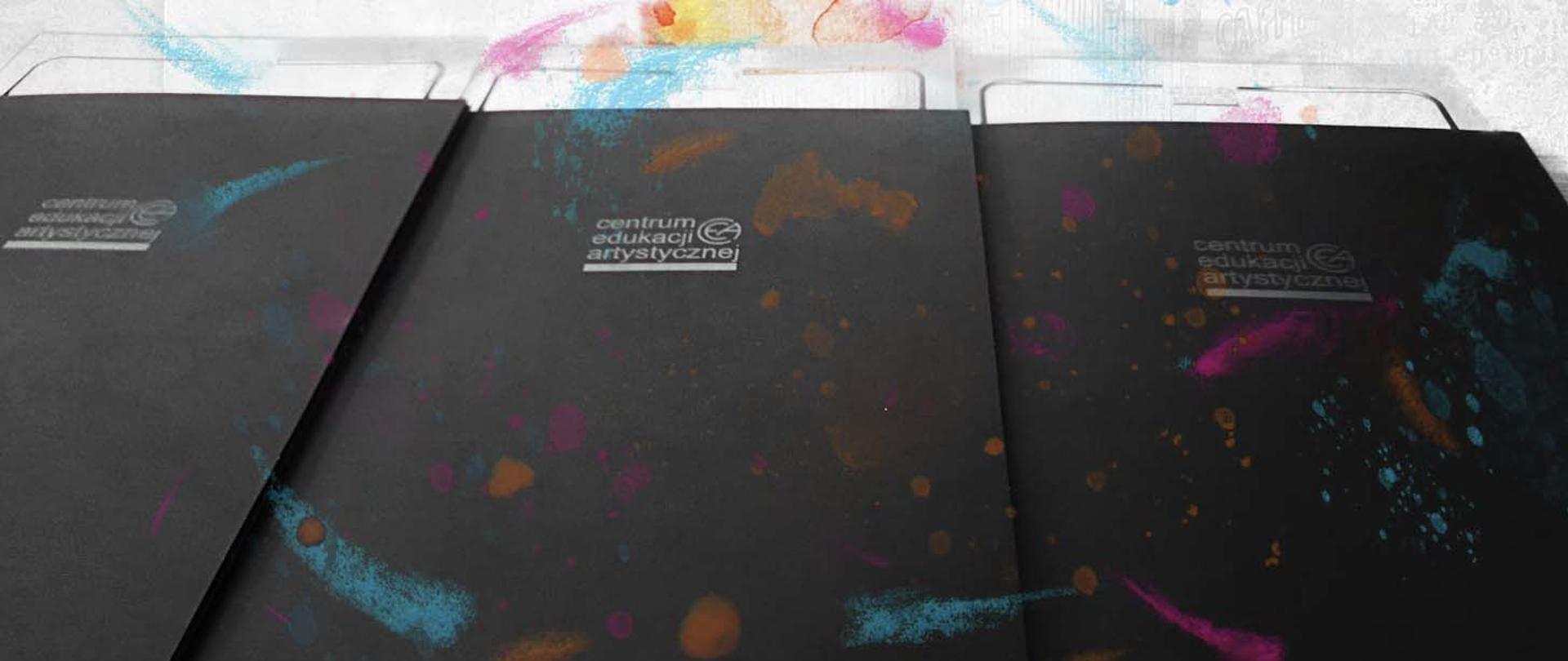 Zdjęcie artystyczne teczek z logo Centrum Edukacji Artystycznej