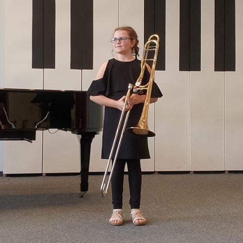 Dziewczynka stoi trzymając w przed sobą puzon