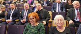 Na zdjęciu widać elegancko ubrane osoby siedzące w audytorium, na pierwszym planie Pani Agnieszka Wąs oraz Pani Franciszka Teresa Skóra.