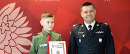 Filip trzymający odznakę i dyplom oraz Śląski Komendant Wojewódzki PSP nadbryg. Jacek Kleszczewski 