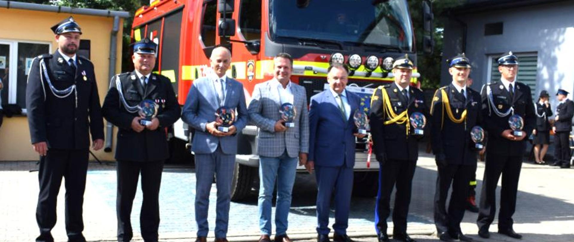 Zdjęcie pamiątkowe gości honorowych na tle przekazanego wozu