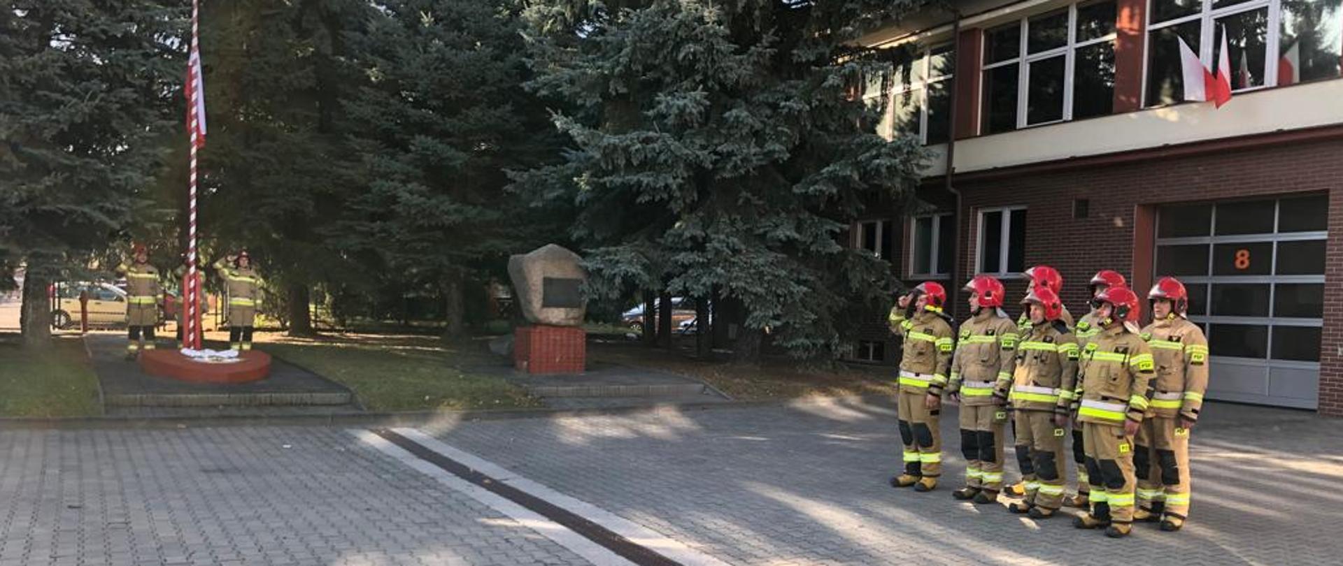 Zdjęcie przedstawia strażaków Jednostki Ratowniczo-Gaśniczej Nr 1 w Rzeszowie w umundurowaniu bojowym, stojących w dwuszeregu, przed siedzibą strażnicy podczas uroczystej zbiórki z okazji Narodowego Święta Niepodległości.