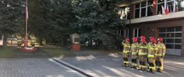 Zdjęcie przedstawia strażaków Jednostki Ratowniczo-Gaśniczej Nr 1 w Rzeszowie w umundurowaniu bojowym, stojących w dwuszeregu, przed siedzibą strażnicy podczas uroczystej zbiórki z okazji Narodowego Święta Niepodległości.