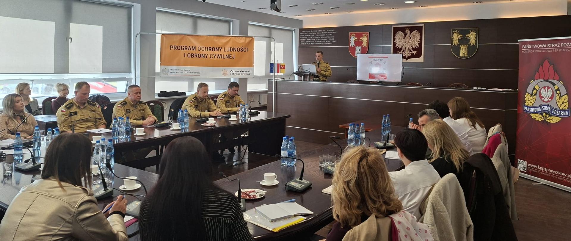 Na zdjęciu przedstawiciele placówek oświatowych oraz służb mundurowych siedzący przy stołach konferencyjnych podczas spotkania w sali sesyjnej starostwa powiatowego.
