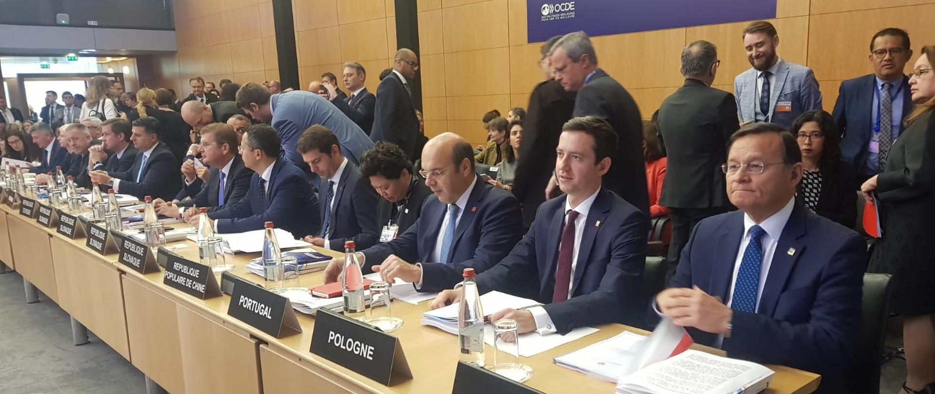 Wiceminister Marcin Ociepa za stołem z innymi uczestnikami sesji ministerialnej Rady OECD w Paryżu. 