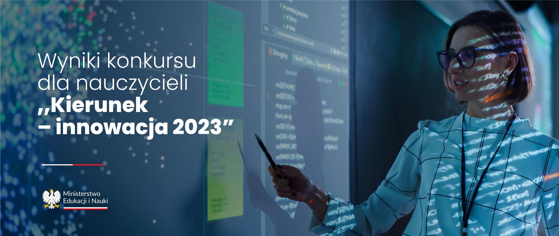 Kobieta pokazująca coś długopisem na dużym ekranie. Na sylwetce i twarzy kobiety widoczne cienie z informacji padających z rzutnika na ekran. Po lewej stronie napis Wyniki konkursu dla nauczycieli „Kierunek – innowacja 2023”
