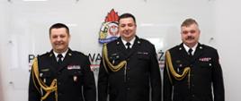 Na zdjęciu stoją w mundurach wyjściowych od lewej strony śląski komendant wojewódzki PSP nadbryg. Jacek Kleszczewski, w środku mł. bryg. Paweł Giendek powołany zastępca komendanta miejskiego PSP w Świętochłowicach i po prawej komendant Miejski PSP w Świętochłowicach bryg. Piotr Skóra. W tle na ścianie widoczne logo PSP.
