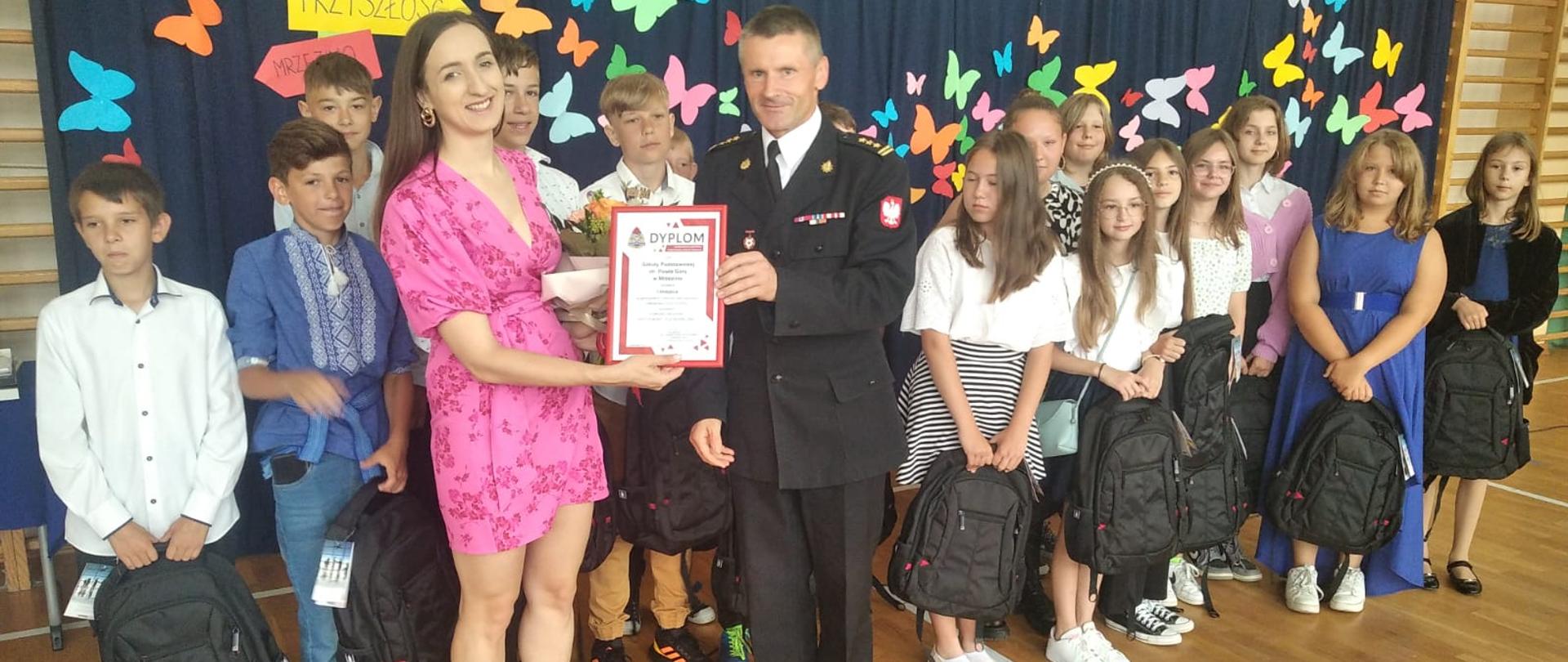Na zdjęciu widać strażaka ubranego w mundur wyjściowy wraz z opiekunką grupy, która wygrała w konkursie.