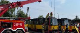 Strażacy przygotowują zawiesia do podniesienia tramwaju. 