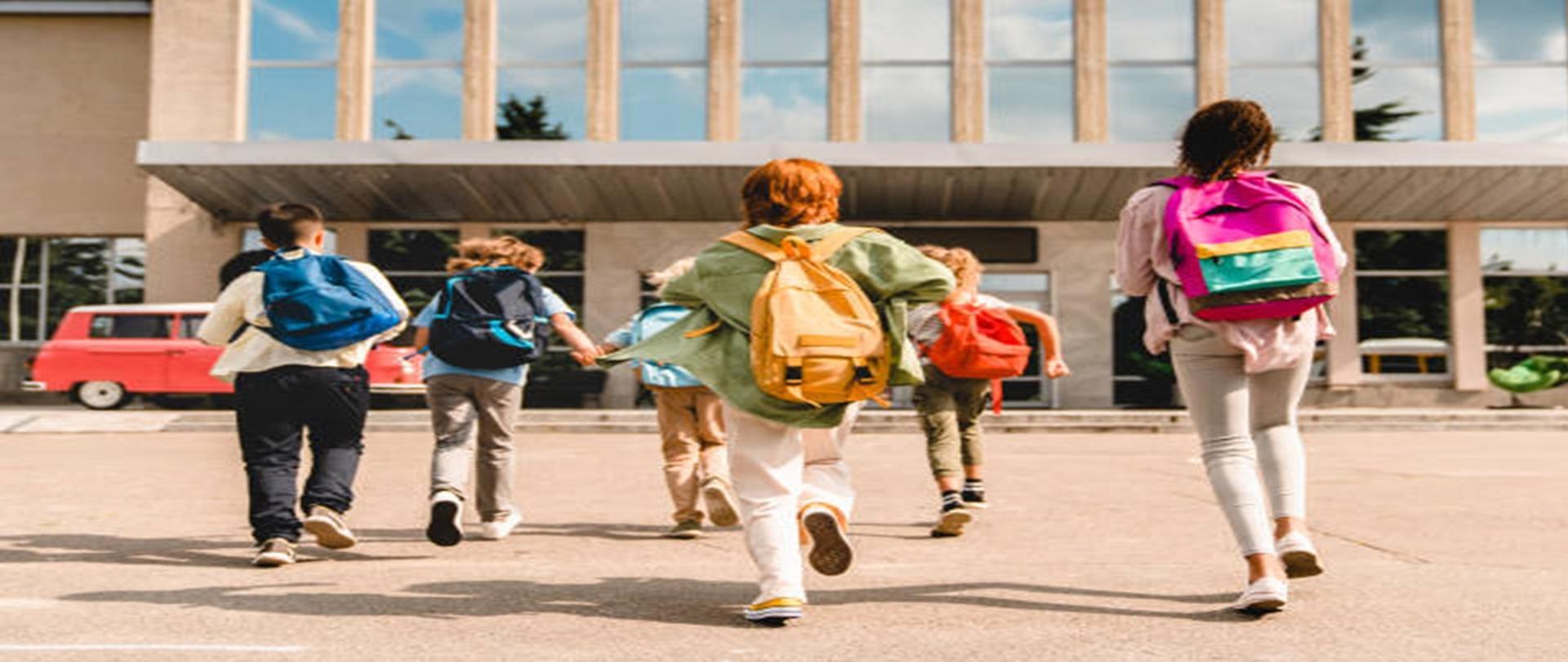 Małe dzieci dzieci w wieku szkolnym uczniowie studenci biegną spiesząc się do budynku szkoły na zajęcia lekcje od do autobusu szkolnego. Witamy z powrotem w szkole. Nowy semestr akademicki rok rozpoczyna się