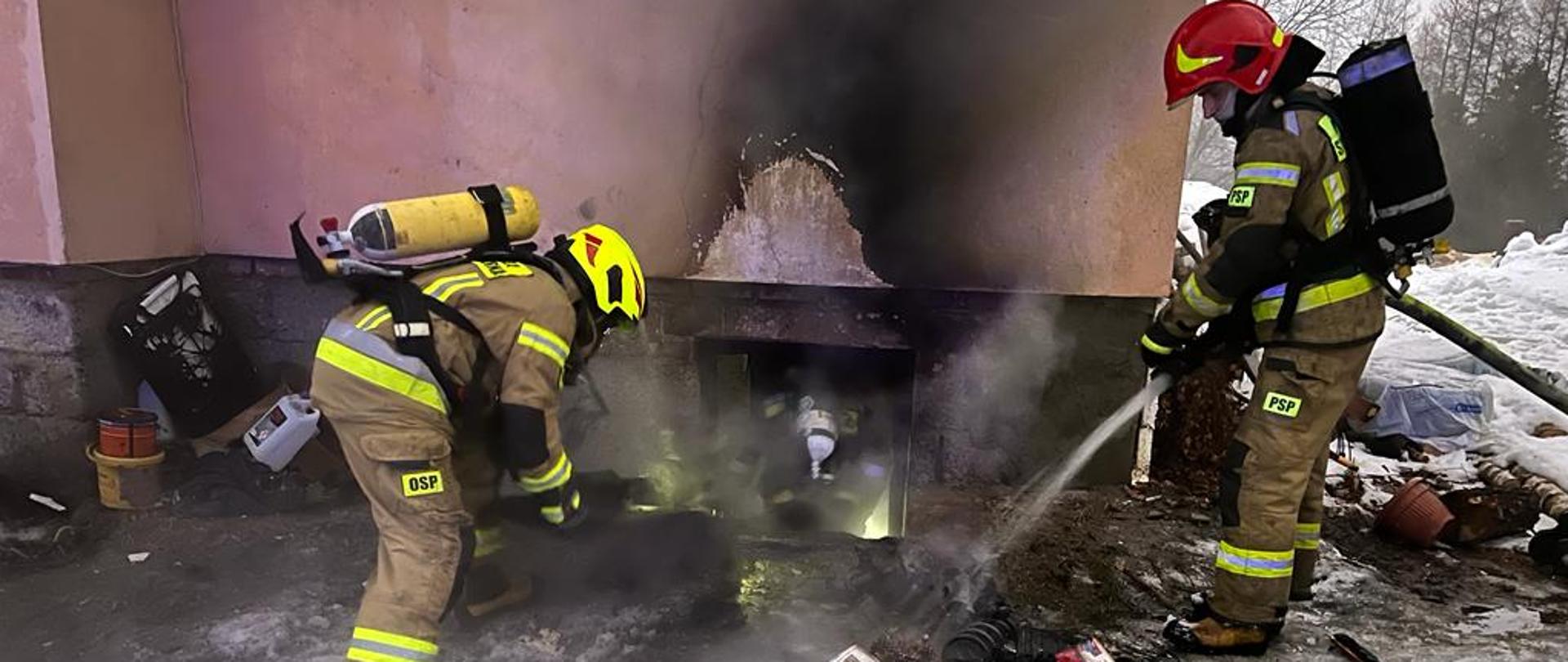 Strażacy gaszą materiały z piwnicy przed budynkiem