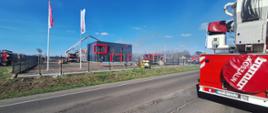 Pożar hali magazynowej. Strażacy z podnośnika podają wodę. Przed budynkiem stoją samochody strażackie