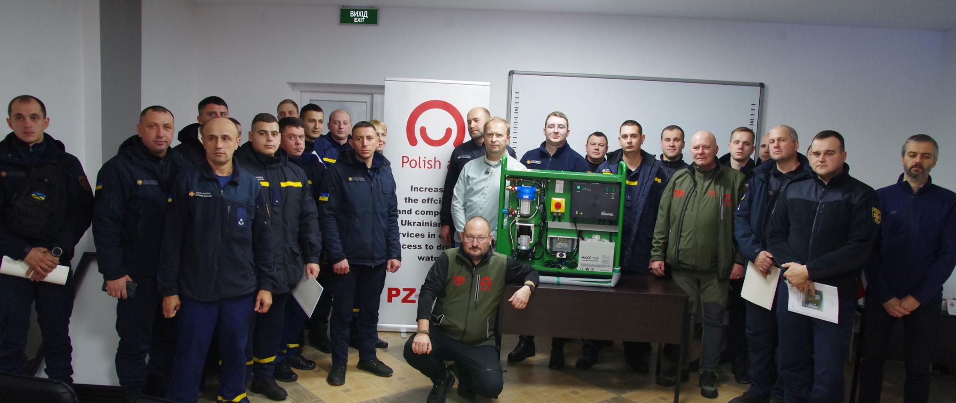 Zdjęcie przedstawia grupę uczestników szkolenia personelu DSNS, w tle baner z logo Polska pomoc