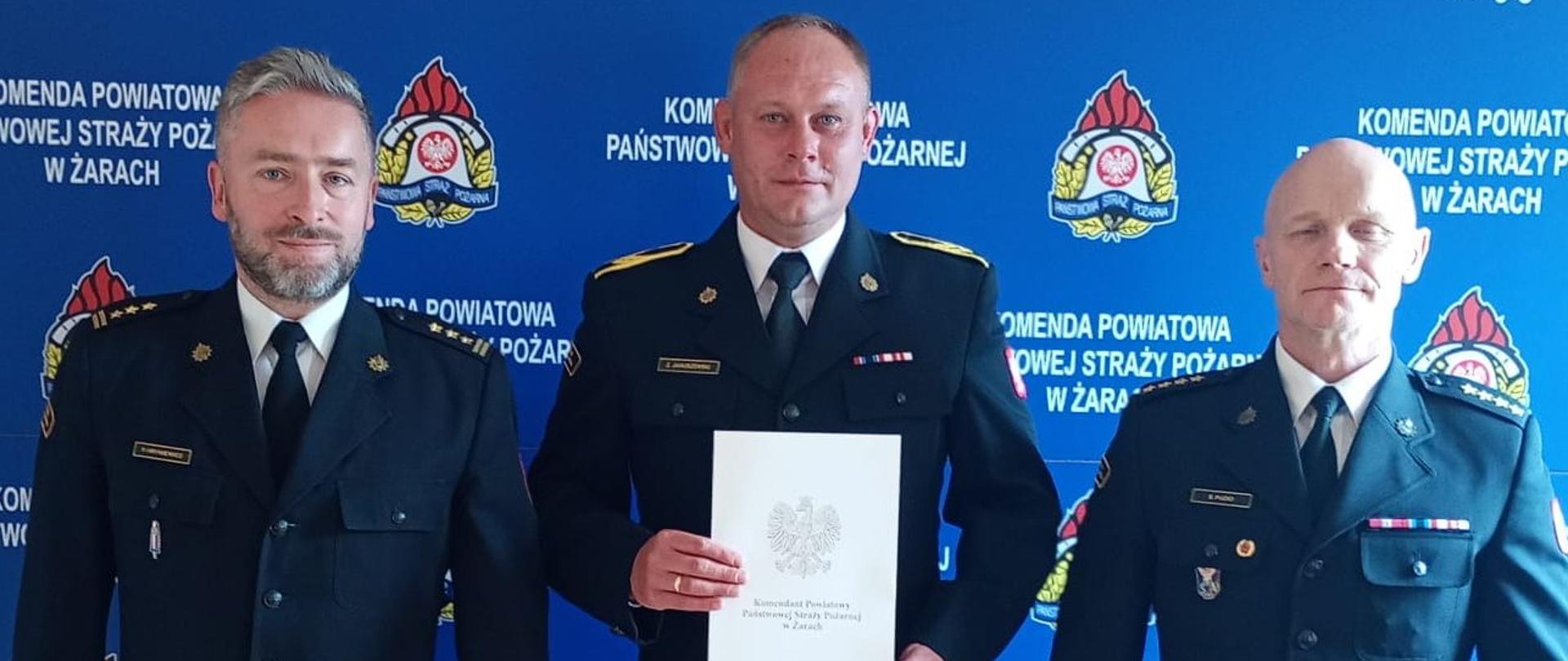 strażak otrzymujący nagrodę z Komendantem i Dowódcą JRG 