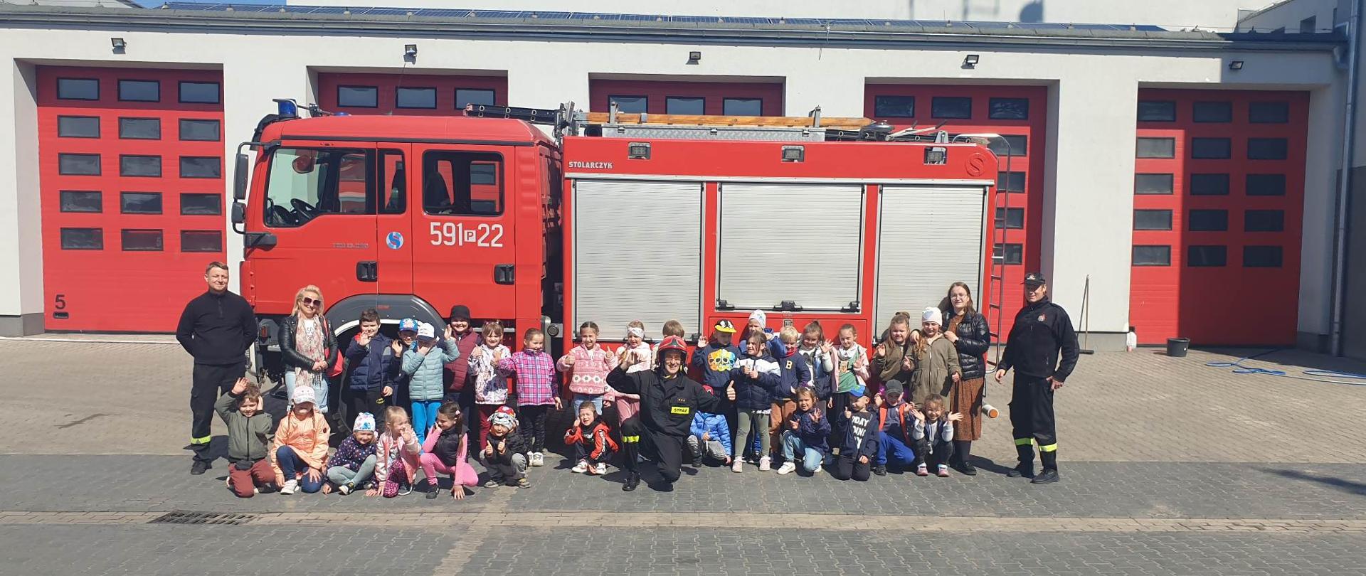 Widać strażaków i dzieci, zdjęcie grupowe na tle samochodu