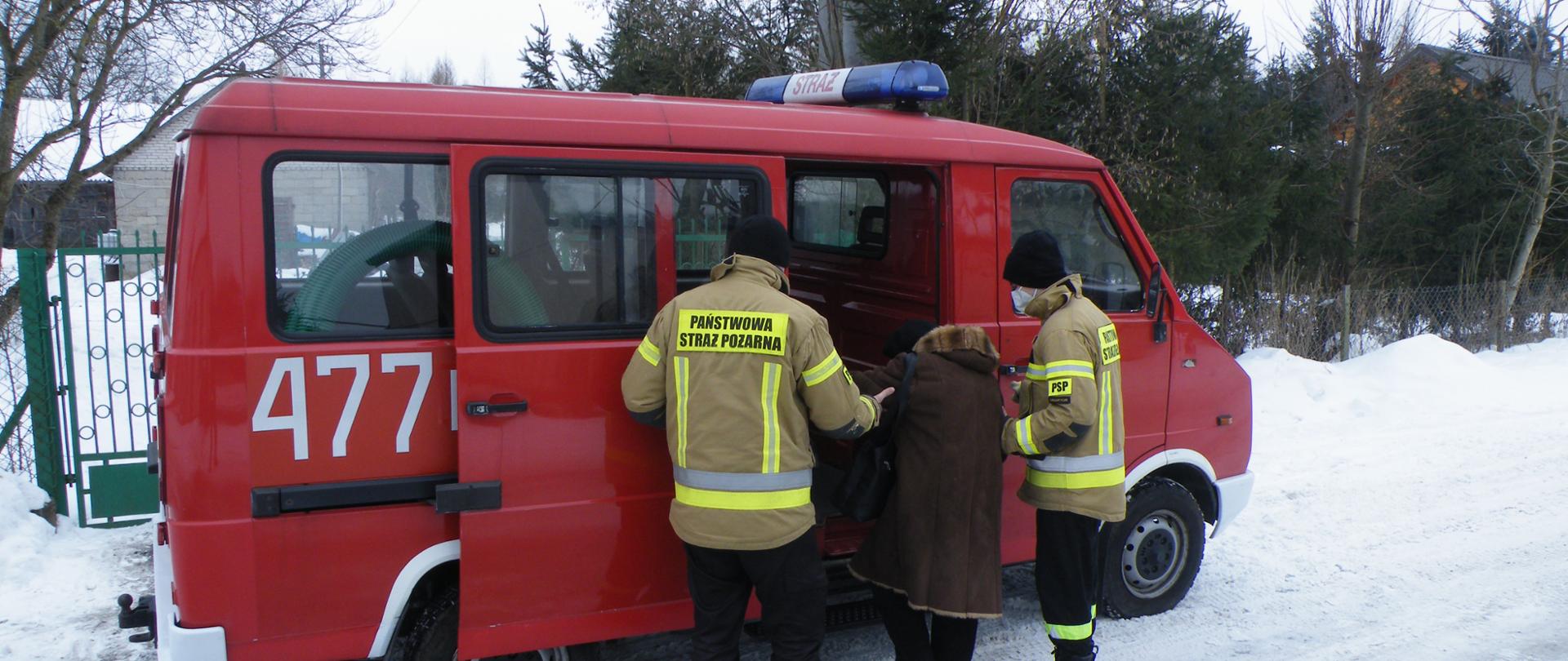 Czerwony samochód pożarniczy dowożący osoby starsze na szczepienie