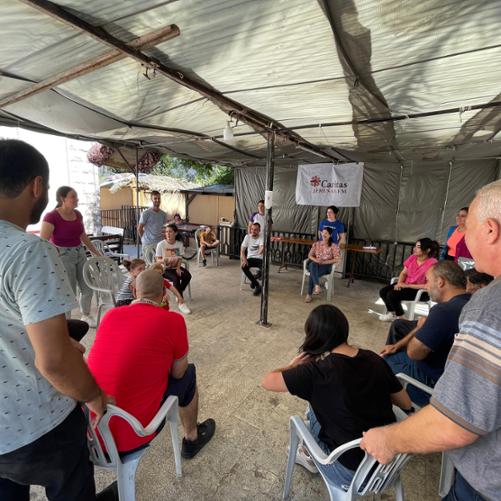 Grupa osób (kobiet i mężczyzn) siedzi na krzesłach ustawionych w koło, rozmawiają