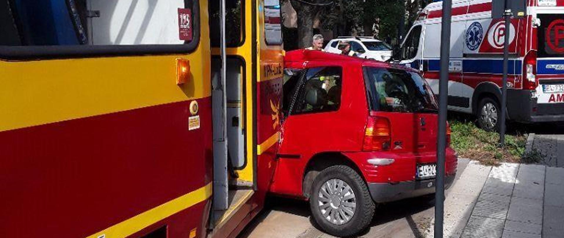 Tramwaj i uderzony prze niego pojazd stojący na torowisku, w tle karetka pogotowia