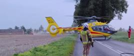 Wypadek na terenie powiatu radziejowskiego. Zdjęcie przedstawia śmigłowiec LPR podczas lądowania oraz strażaka OSP.