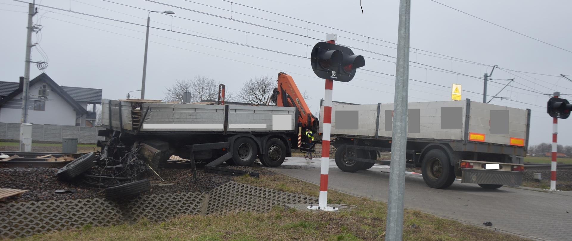 Wypadek śmiertelny na przejeździe kolejowym. Okolice miejscowości Kąty (gm. Rawicz). Na przejeździe kolejowym znajduje się część ładunkowa samochodu ciężarowego (znacznie uszkodzona) oraz podłączona do niej przyczepa. Na samochodzie, na którym przewożone były europalety, zamontowany jest HDS. Część towaru rozrzucona jest na torowisku. W tle zabudowania