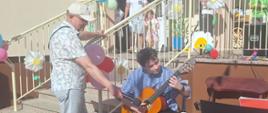 Paweł Matysiak gra na gitarze pan J. Goerlich trzyma mikrofon