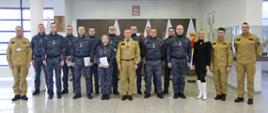 Grupowe zdjęcie uczestników szkolenia (12 osób) w towarzystwie Zastępcy Komendanta Centralnej Szkoły PSP, kobiety oraz trzech strażaków CS PSP