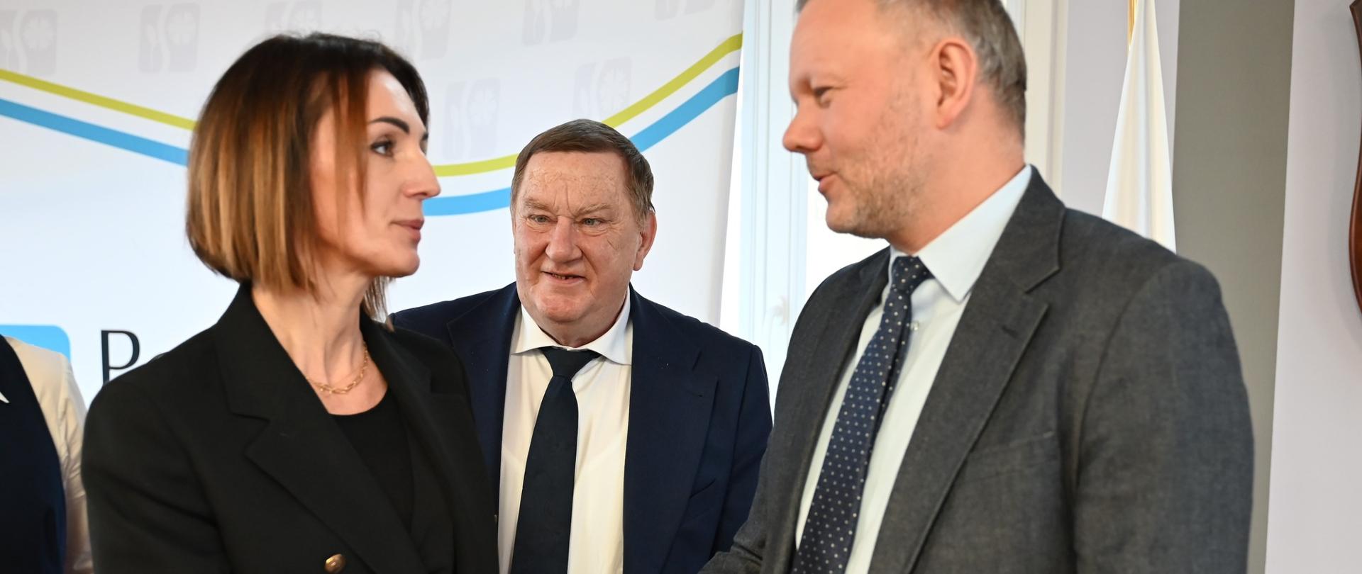 kobieta (wojewoda) wita się z mężczyzną w tle inny mężczyzna i tablica z napisem powiat starogardzki