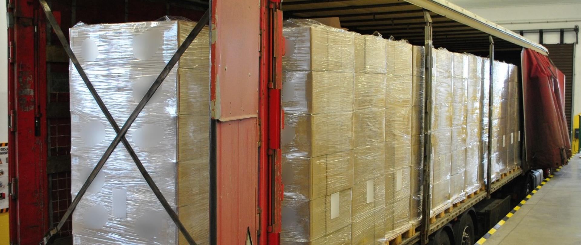 Otwarta naczepa, w środku kartony na paletach.