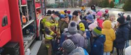Na zdjęciu strażacy pokazują dzieciom samochód ratowniczy oraz sprzęt