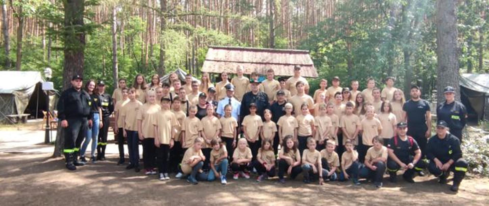 zdjęcie grupowe - członkowie Młodzieżowych Drużyn Pożarniczych ubrani w koszulki z napisem straż, w środku Zastępca Śląskiego Komendanta Wojewódzkiego PSP st. bryg. Rafał Świerczek, Komendant Powiatowy PSP w Pszczynie st.bryg. Grzegorz Kołoczek oraz druhny i druhowie OSP