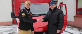 Komendant Centralnej Szkoły PSP przekazuje kluczyki do samochodu druhowi OSP, w tle przekazywany samochód marki Ford Transit