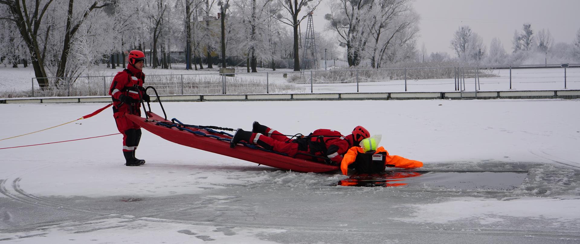 Strażacy podejmujący fantoma z przerębla przy pomocy deski lodowej według obowiązujących w PSP zasad.