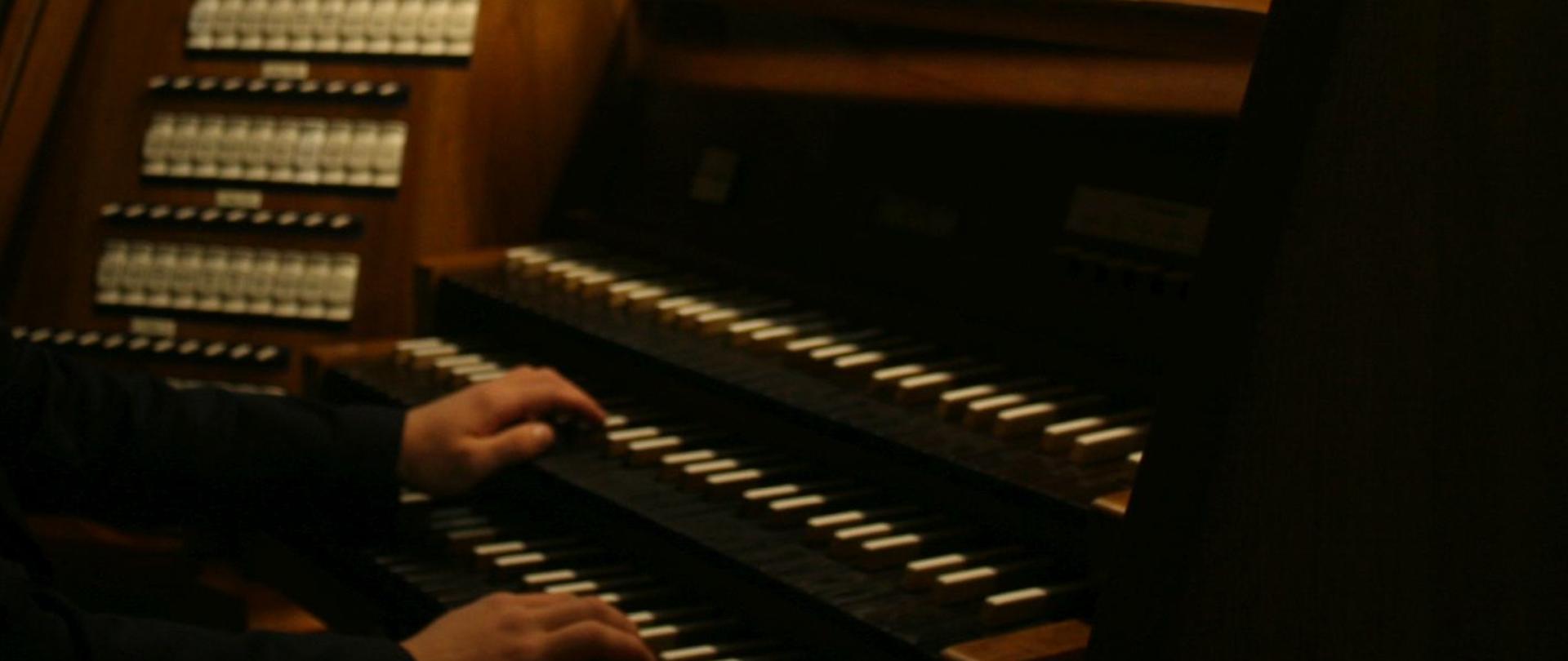 zdjęcia pokazują uczestników koncertu - Dominika Tomę, Michała Sosnę oraz Mikołaja Kowalskiego siedzących przy kontuarze organów w kościele pod wezwaniem św. Józefa Robotnika w Katowicach. Panuje tam półmrok, wszyscy trzej są ubrani w ciemne, eleganckie stroje.