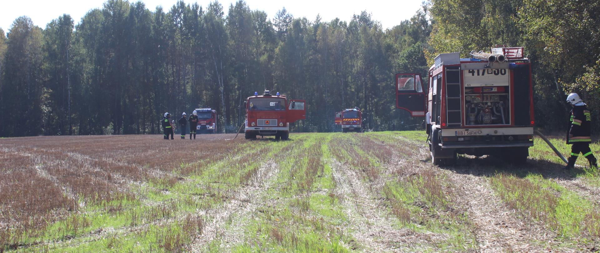 Zdjęcia przedstawia wozy ratowniczo-gaśnicze na ściernisku w pobliżu lasu podczas ćwiczeń gaszenia lasu 