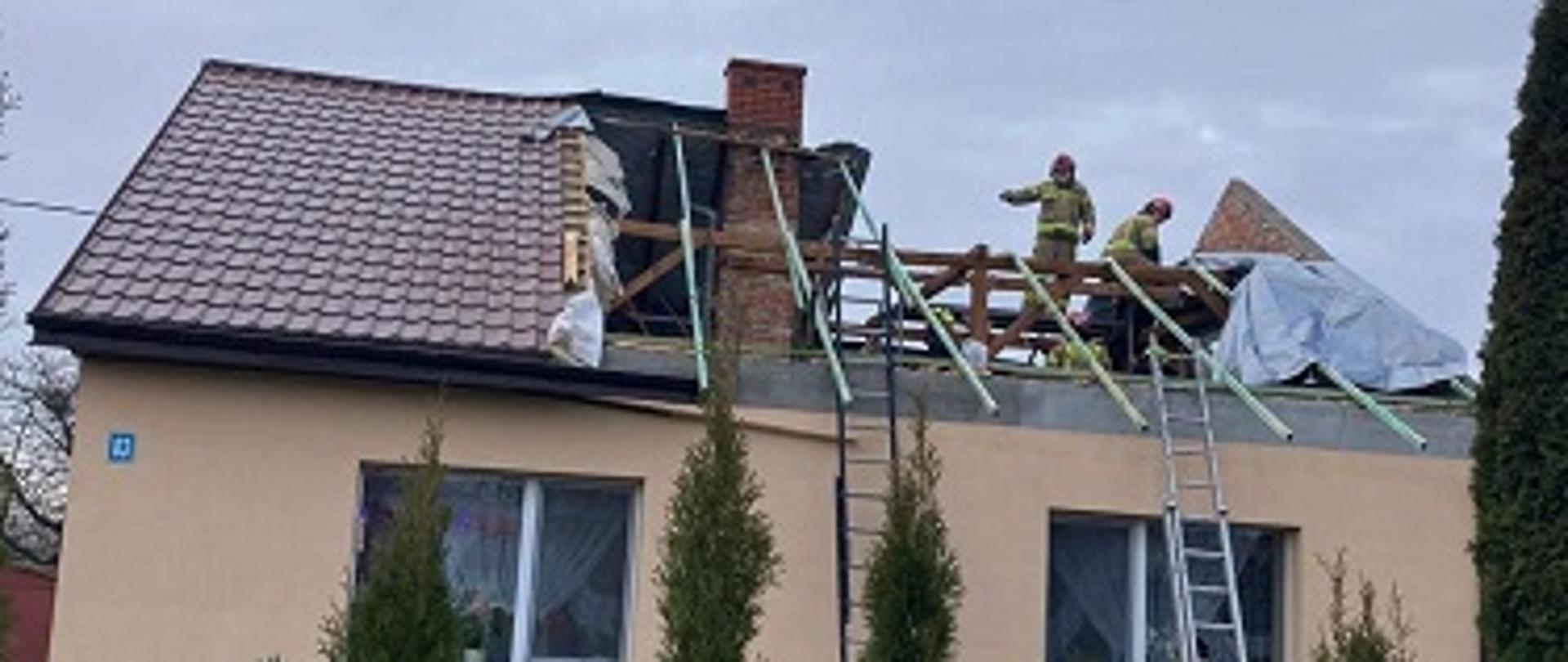Na zdjęciu strażacy zabezpieczający zerwany dach na budynku mieszkalnym jednorodzinnym.