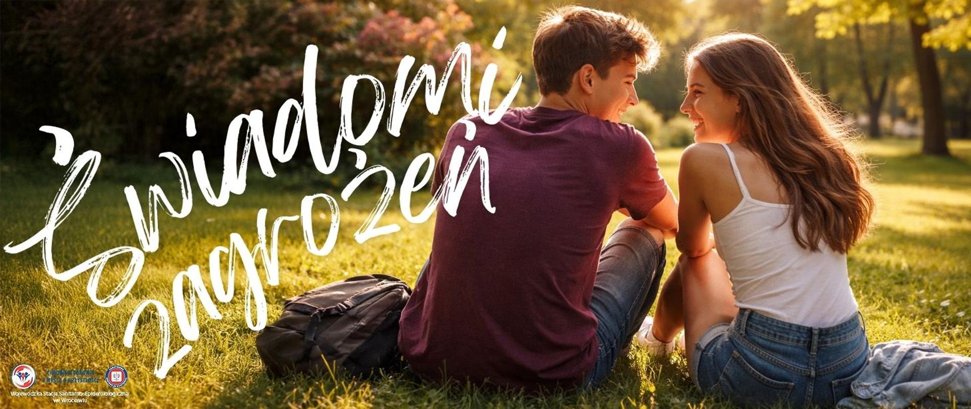 Dwoje młodych ludzi siedzi obok siebie na trawie w parku, tyłem do oglądającego. Ich sylwetki są blisko siebie, ciała lekko pochylone w stronę rozmówcy, co sugeruje intymność i napięcie pełne ciekawości. Wokół nich rozpościera się jasny, słoneczny park – drzewa, kwitnące krzewy i lekki powiew wiatru unoszący włosy.