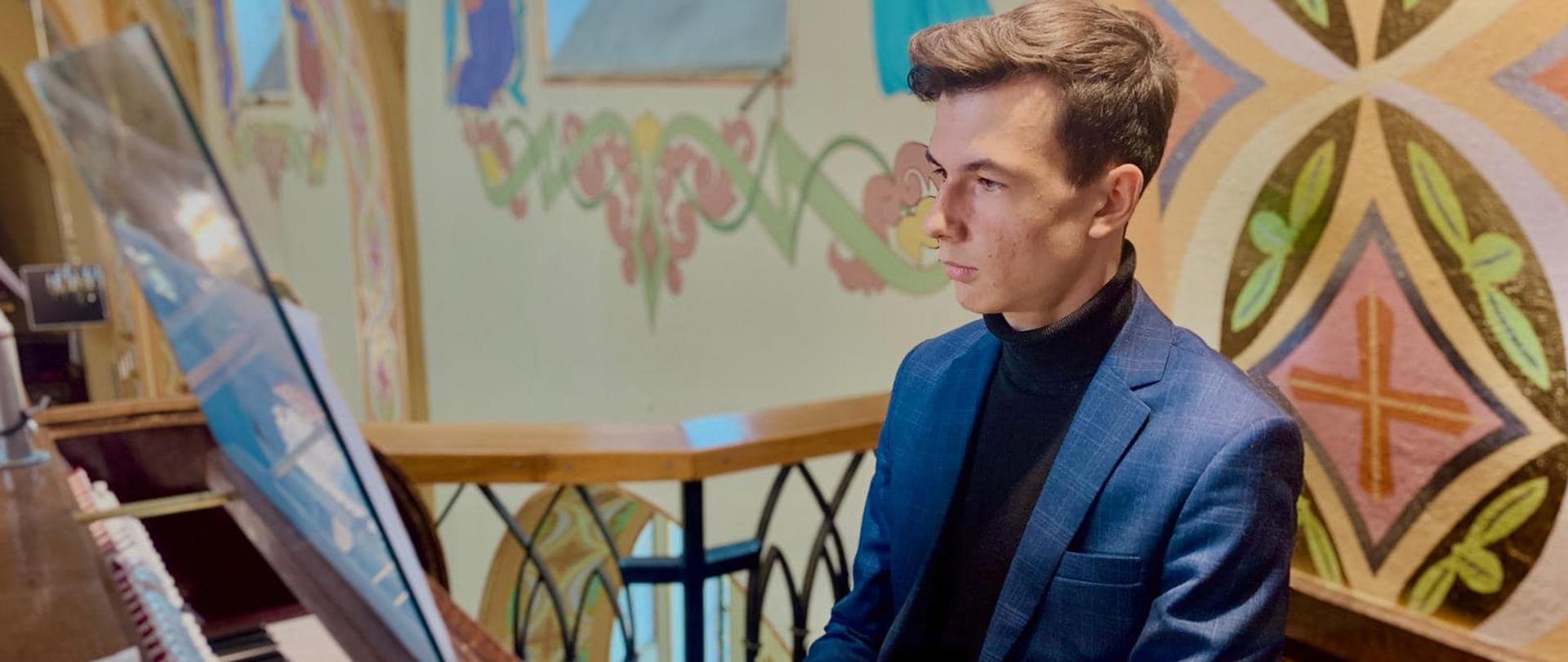 Uczeń siedzi przy organach, ręce trzyma na klawiaturze.